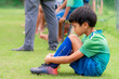Sad soccer kid sitting on field side substitution bench doesn't get to play in a competition match