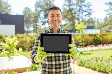 Canvas Print - gardening and people concept - happy smiling middle-aged man showing tablet pc computer at summer garden