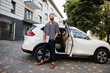 © AS Photo Family - Successful arab man wear in striped shirt and sunglasses pose near his white suv car with laptop in hands.
