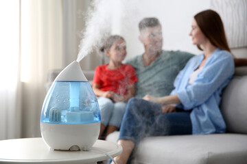 Modern air humidifier and blurred family on background