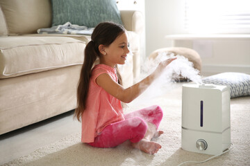 Wall Mural - Little girl near modern air humidifier at home