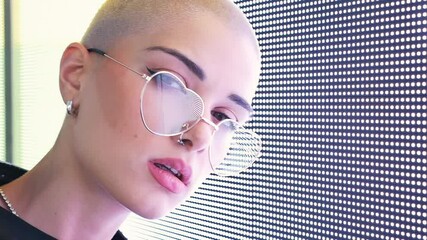 Wall Mural - beautiful young woman posing against a led panel. Shaved head teenager with alternative look making urban portraits