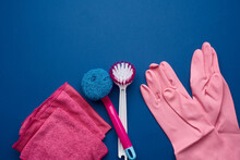 Pink Rubber Gloves For Cleaning, Pink Sponges, Brushes On A Blue Background