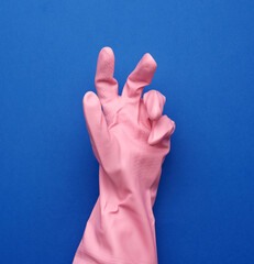 Wall Mural - pink rubber glove for cleaning dressed on a female hand