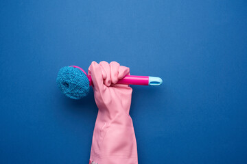 Wall Mural - hand in a pink rubber glove for cleaning a house holds plastic brush with a handle