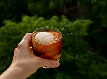 Classic Home-made Old Fashioned Alcohol Drink With Ice Ball And Orange Zest, Trees Sky And Rain Drops. Stay At Home Balcony Bad Weather Cocktail Party. Good For Website Blog Recipes Articles