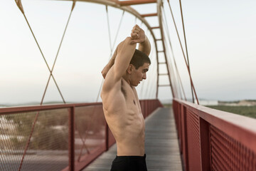 Wall Mural - Runner stretching after training on red bridge