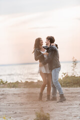 Wall Mural - Selective focus of young couple in leather jackets hugging on beach at dawn