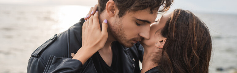 Wall Mural - Horizontal crop of woman touching neck of boyfriend beside sea