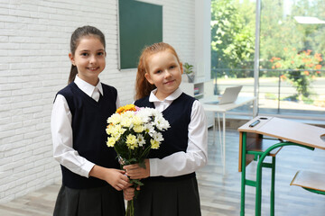 Wall Mural - Happy schoolgirls with bouquet in classroom. Teacher's day