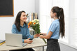 © New Africa - Schoolgirl congratulating her pedagogue with bouquet in classroom. Teacher's day