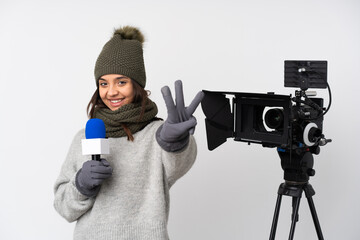 Reporter woman holding a microphone and reporting news over isolated white background happy and counting three with fingers