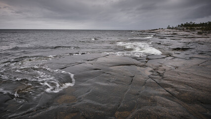 Wall Mural - wet cliffs in the foreground and the sea in the background, cloudy weather