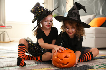 Sticker - Cute little girls with pumpkin head jack lantern wearing Halloween costumes at home