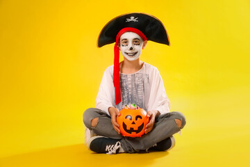 Poster - Cute little boy with pumpkin candy bucket wearing Halloween costume on yellow background