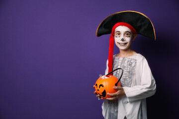 Canvas Print - Cute little boy with pumpkin candy bucket wearing Halloween costume on purple background. Space for text