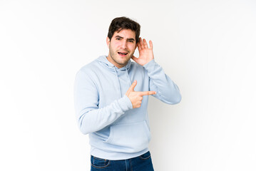 Wall Mural - Young man isolated on white background trying to listening a gossip.