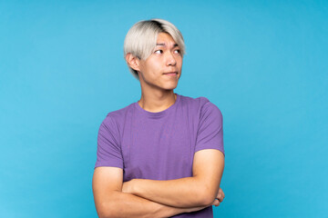 Wall Mural - Young asian man over isolated blue background making doubts gesture while lifting the shoulders