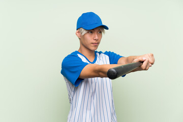 Wall Mural - Young asian man playing baseball over isolated green background