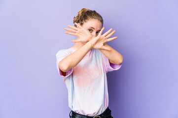 Wall Mural - Young caucasian woman on purple background keeping two arms crossed, denial concept.