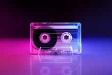 Retro Audio Cassette Tape Lit By Pink And Blue Lamps On A Black Background With Reflection