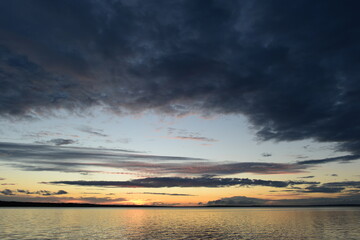 Wall Mural - Cold colors sky in dark clouds  on the sunset  above the lake water