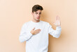© Asier - Young caucasian man isolated on beige background taking an oath, putting hand on chest.