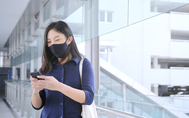 woman wear mask using a smartphone,on footbridge