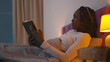 Beautiful young african woman reading book before going to sleep.