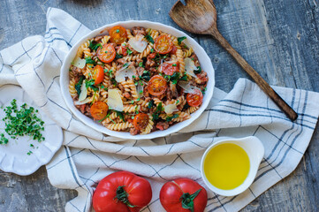 tasty italian lunch or dinner - pasta with bolognese tomato sauce and parmesan cheese served with micro green and cherry tomatoes on rustic wooden background