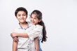 Indian asian cute little siblings embracing while wearing white cloths against white background
