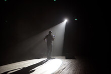 Stand Up Comedian On Stage In The Beam Of Light.