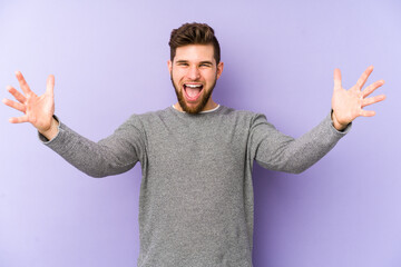 Wall Mural - Young caucasian man isolated on purple background celebrating a victory or success, he is surprised and shocked.