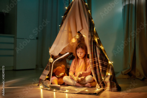 Cuadros en Lienzo A cute girl wearing pyjamas sitting on a floor cross-legged barefoot in a self-m