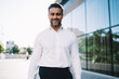 © BullRun - Half length portrait of cheerful businessman 40 years old dressed in white shirt smiling at camera in financial district, happy Caucasian male employer in formal clothes posing in city downtown