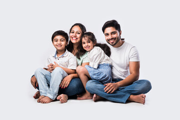 Wall Mural - Portrait of young Indian family of Four looking at camera on white background