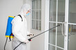 © ake - health care worker in white jumpsuit and protective face mask using spraying machine to disinfect virus pandemic.  Health care and midicine concept. New normal social distancing concept.
