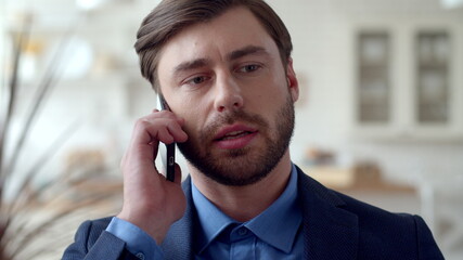 Attractive business man making phone call at home. Guy talking on cellphone