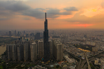 Aerial urban colorful sunrise panorama with high rise building disappearing into the clouds, city center skyline and suburban sprawl