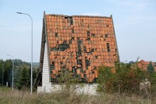 A House With A High Sloping Red Tiled Roof. Destroyed Roof With Falling Tiles.