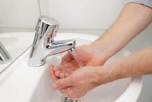 Man Washing Hands In Bathroom Sink At Home