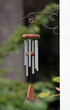 Decorative metal and wooden wind chimes hung outside from a curling hook