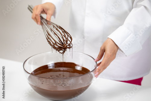 Fotomural Chef whisking melted premium Belgian dark chocolate in glass mixing bowl using old vintage wire whisk