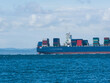 © unite images/Stocksy - cargo ship on the ocean with coast in background