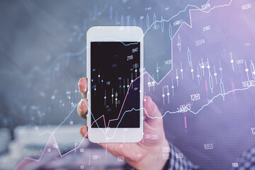 Double exposure of man's hands holding and using a digital device and forex graph drawing. Financial market concept.