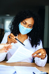 Wall Mural - Portrait of a business woman working at meeting sitting at desk reading  contract wearing face mask