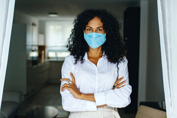 Wall Mural - Portrait of a woman standing indoors wearing face mask with arms crossed