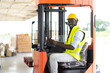 © NVB Stocker - Warehouse man worker driver forklift. warehouse worker driver stacking card boxes by forklift in warehouse store. African American black people.