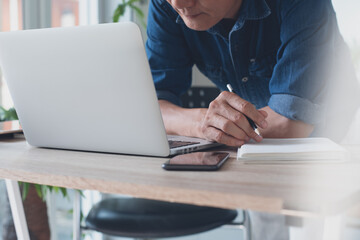 Asian business man online working on laptop computer from home office