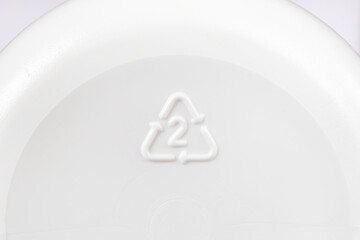 A triangle recycling icon with number 2 seen on the bottom of a plastic bottle indicating it's made of high-density polyethylene, or HDPE, a recyclable plastic material and safe for reuse. Macro view.